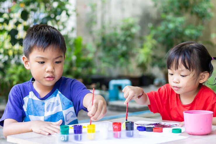 Aziatische broer of zus kinderen tekenen en schilderen van kleuren op het papier in de kamer.