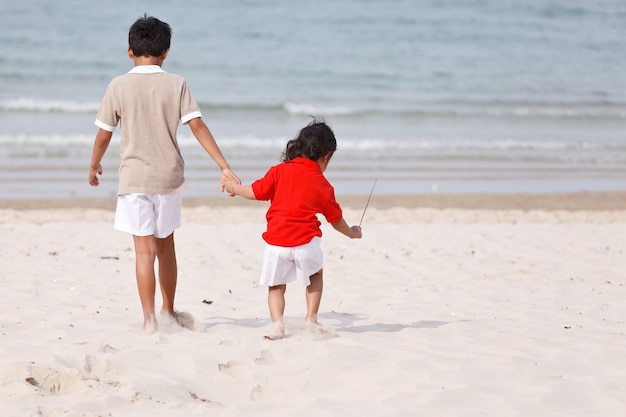 Aziatische broers hand in hand op tropisch strand