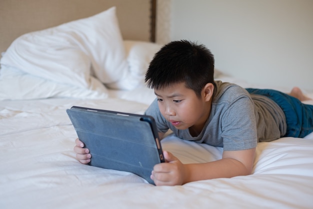Aziatische Chinese jongen die smartphone speelt, kind gebruikt telefoon en speel spel, verslaafd spel en tekenfilm