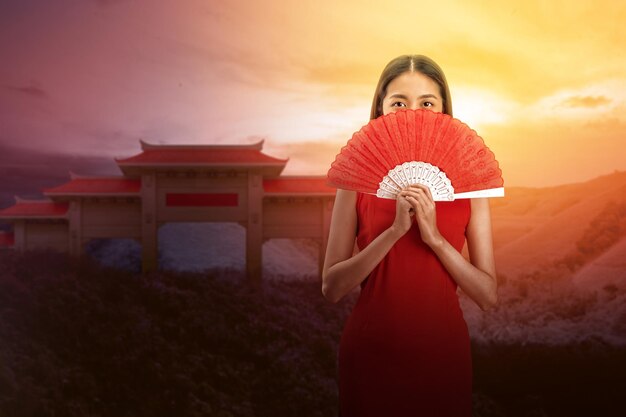 Aziatische Chinese vrouw in een cheongsam-jurk met ventilator viert Chinees Nieuwjaar. Gelukkig Chinees nieuwjaar