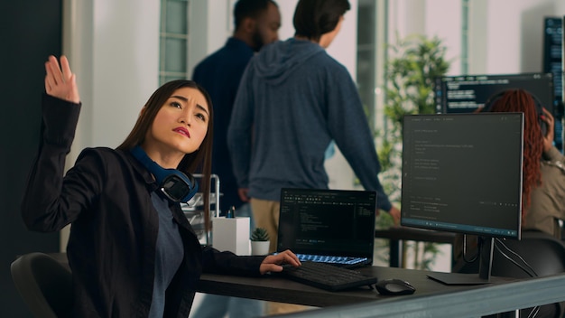 Aziatische coder draait hoofd om te werken met holografische servercode, html-script typend in terminalvenster. Software-engineer die werkt met hologram van app-database, systeemalgoritme schrijft.