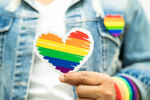 Aziatische dame die regenboogvlagpolsbandjes draagt en een rood hartsymbool van de LGBT-trotsmaand vasthoudt, viert jaarlijks in juni sociaal van homo-lesbische biseksuele transgender mensenrechten