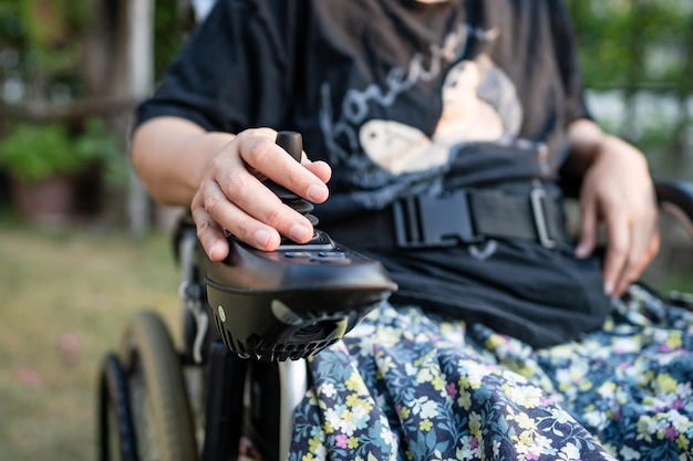 Aziatische dame vrouw patiënt op elektrische rolstoel met joystick en afstandsbediening op verpleegafdeling gezond sterk medisch concept