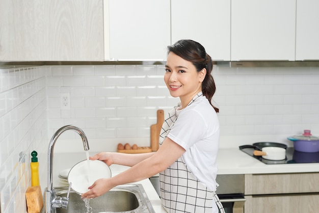 Aziatische dame wast een gerecht in de keukenkamer