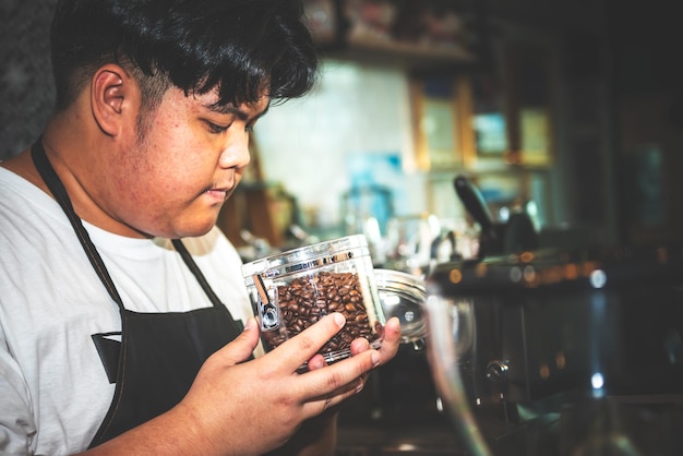 Aziatische dikke man Coffeeshopeigenaar die op zoek is naar kwaliteitskoffiebonen die zijn geroosterd en gekookt, in een glazen pot, voor mensen en drankconcept.