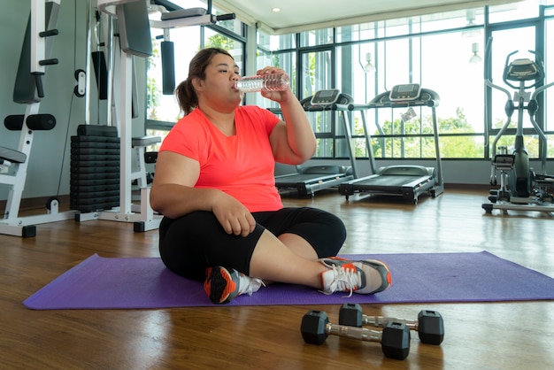 Aziatische dikke vrouw vecht overgewicht in de sportschool, zware fitness oefeningen doen