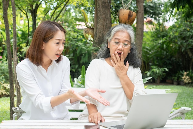 Aziatische dochter leert oude oudere vrouw online te gebruiken Sociale media in computerlaptop