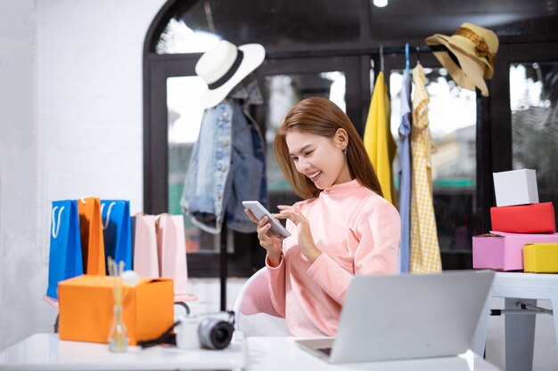 Aziatische een smartphone gebruiken en vrouw die terwijl het zitten in workshop glimlachen