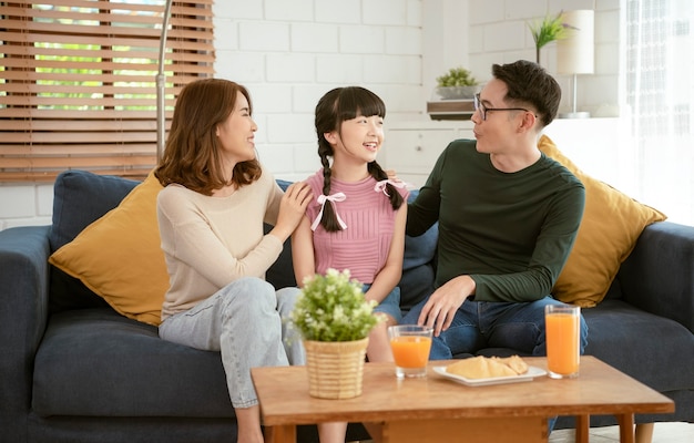 Aziatische en gelukkige familie die samen op bank thuis woonkamer zitten.