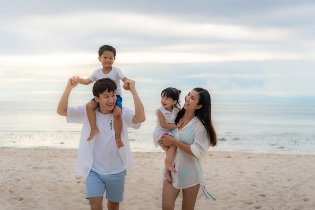 Aziatische en gelukkige familie op vakantie op het strand