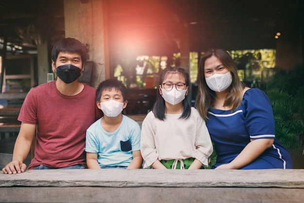 Aziatische familie die een gezichtsmasker draagt dat in een Thais huis zit