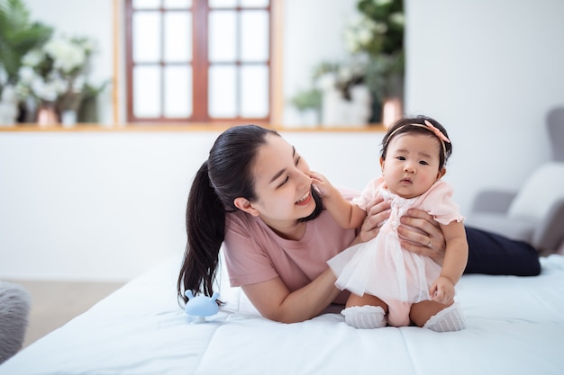 Aziatische familie en moederschap concept gelukkig lachende jonge Aziatische moeder met kleine baby thuis