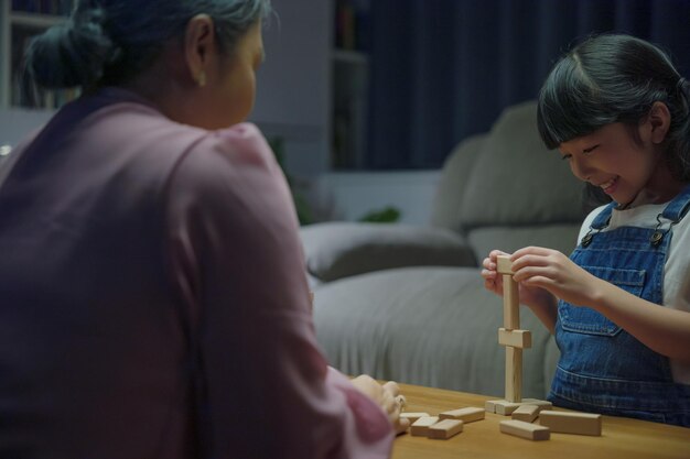 Aziatische familie geniet van het spelen van speelgoedblokken met dochtertje samen in de huiskamer