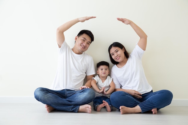Aziatische familie glimlachend en spelend huis met de hand op geïsoleerde witte achtergrond