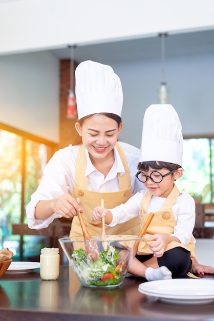 Aziatische familie in de keuken. Moeder leert zoon om gezond voedsel te koken in de zomervakantie.