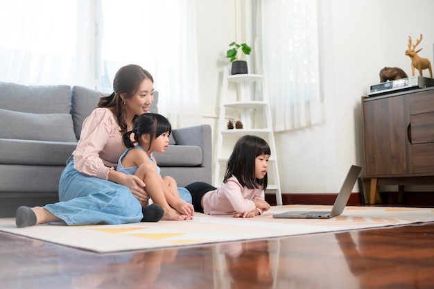 Aziatische familie met kinderen die laptop computer thuis gebruiken