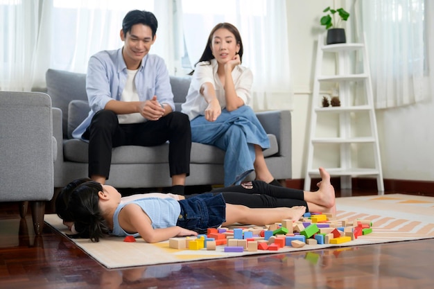 Aziatische familie met kinderen die spelen en een toren bouwen van kleurrijke houten speelgoedblokken in de woonkamer