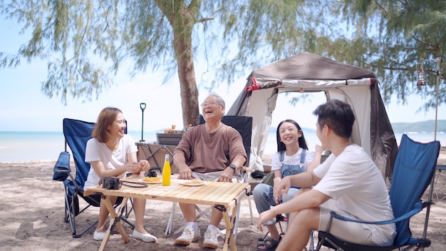 Aziatische familie met senior en kinderen ontspannen en kamperen op tropisch strand tijdens zomervakantie. Saamhorigheid en outdoor activiteit levensstijl.