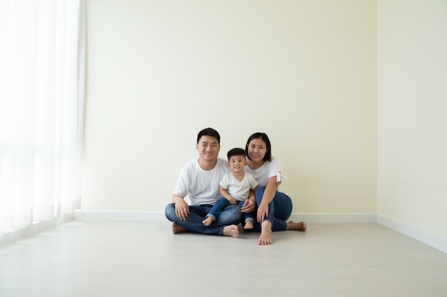 Aziatische familie zittend op de vloer in de nieuwe kamer en het nieuwe huis, verhuizing en onroerend goed concept