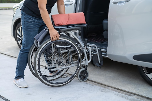 Aziatische gehandicapte vrouw op rolstoel die in haar auto stapt Toegankelijkheidsconcept