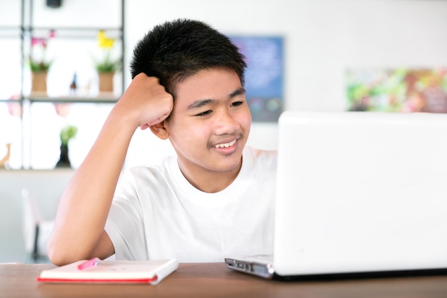 Aziatische gelukkige jongensstudent draagt een koptelefoon en studeert online met laptop en tablet met leraar