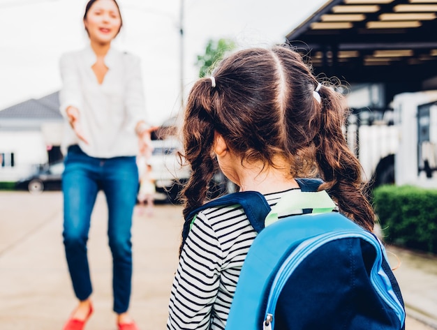 Aziatische gelukkige moeder met handen omhelst haar nadat kinderen terug naar school zijn gegaan