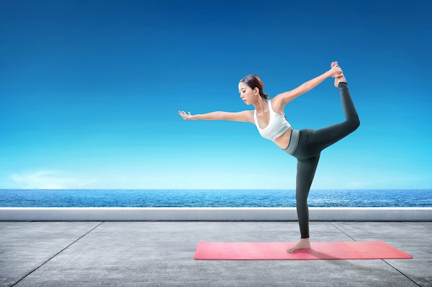 Aziatische gezonde vrouw het praktizeren yoga op het tapijt bij terras