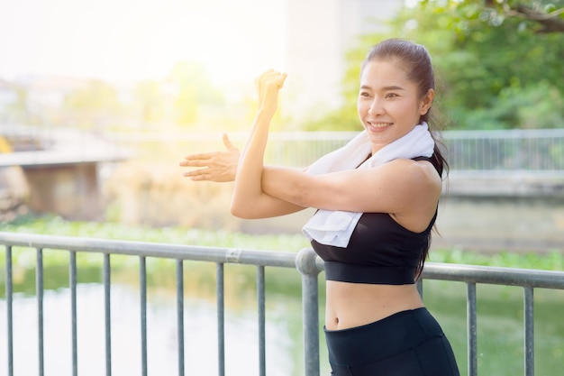 Aziatische gezonde vrouw schouder Stretching oefening in park buiten ochtend