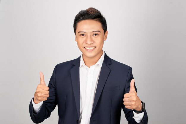 Aziatische glimlachende zakenman die duim beide hand toont die op witte achtergrond wordt geïsoleerd