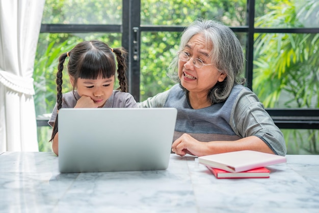 Aziatische grootmoeder met haar twee kleinkinderen die plezier hebben en online educatieve spelletjes spelen