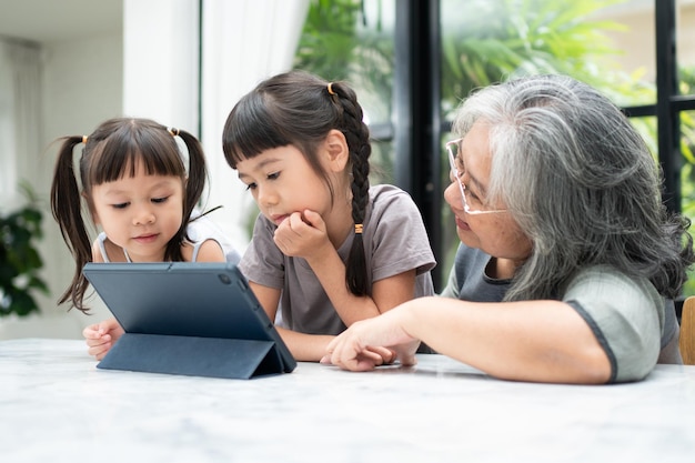 Aziatische grootmoeder met haar twee kleinkinderen die plezier hebben en online educatieve spelletjes spelen