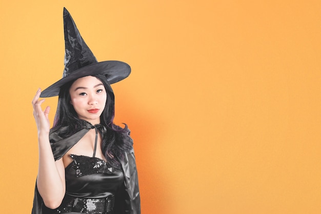 Aziatische heksenvrouw met een hoed die zich met een gekleurde achtergrond bevindt