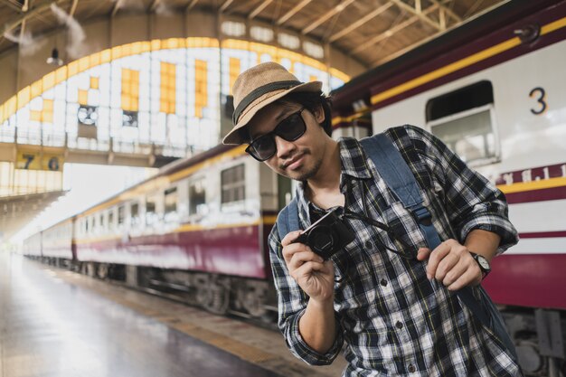 Aziatische het pakoerist van de mensenzak met camera in station in Thailand.