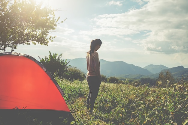 Aziatische hipster schattige tienermeisje die zonsopgang buiten de tent geniet. kamperen in het bos.