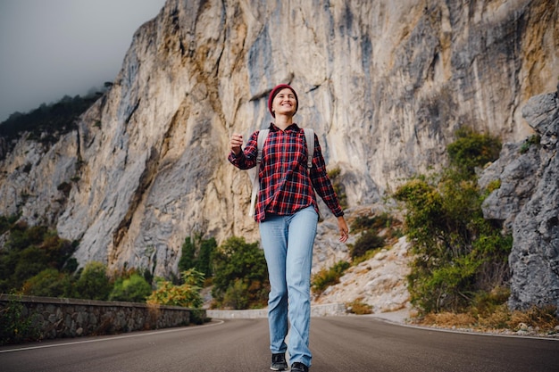 Aziatische hipstervrouw die alleen op een bergweg loopt op een mistige herfstdag