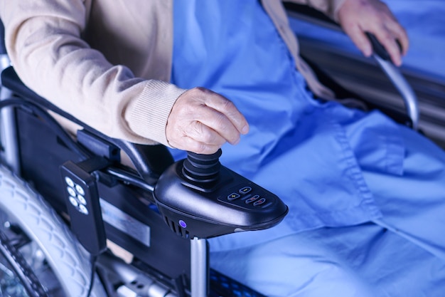 Aziatische hogere dame van de damevrouw patiënt op elektrische rolstoel bij het pleegziekenhuis.