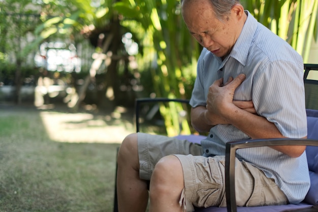 Foto aziatische hogere mens die pijn voelt die aan hartaanval lijdt.