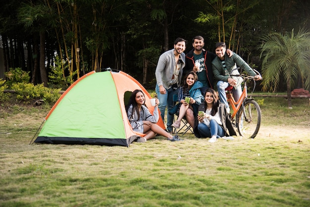 Aziatische Indiase jonge vrienden hebben veel plezier op een kampeertrip, een ontspannende vakantie met leuke buitententen