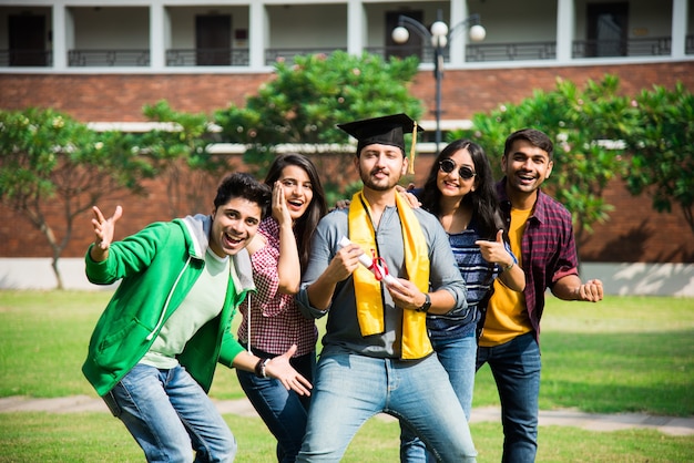 Aziatische Indiase universiteitsstudenten ontvangen diploma terwijl vrienden buiten op de universiteitscampus vieren