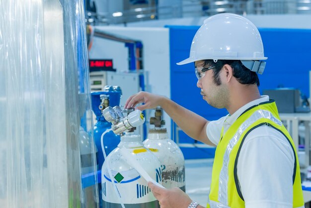 Aziatische ingenieur aan het werk bij OperatiehalThailand mensen dragen helmwerk Hij werkte met toewijding en geduld Hij controleerde de klepregelaar bij de waterstoftank