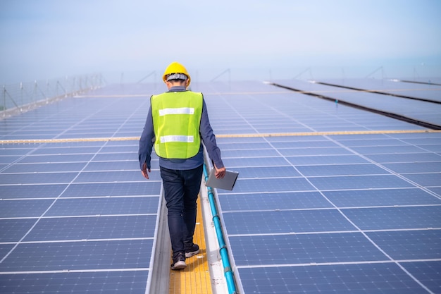 Aziatische ingenieur die de energie van zonne-energiecellen controleert op het dak van de fabriek Aziatische werknemer die werkt, installeert zonne-energie zonnecelsysteem voor het gebruik van schone zonne-energie
