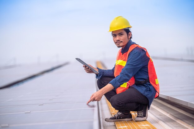 Aziatische ingenieur die de energie van zonne-energiecellen controleert op het dak van de fabriek Aziatische werknemer die werkt, installeert zonne-energie zonnecelsysteem voor het gebruik van schone zonne-energie