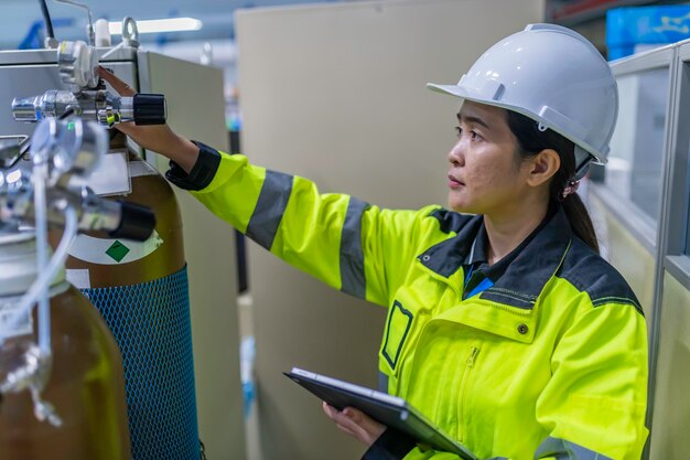 Aziatische ingenieur die in de bedieningszaal werkt. Thaise mensen dragen helmen. Hij werkte met ijver en geduld. Hij controleerde de klepregelaar bij de waterstoftank.