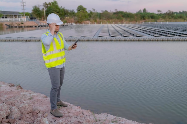 Aziatische ingenieur die werkt bij drijvend zonneparkhernieuwbare energietechnicus en investeerder zonnepanelen die de panelen controleren bij zonne-energie-installatie