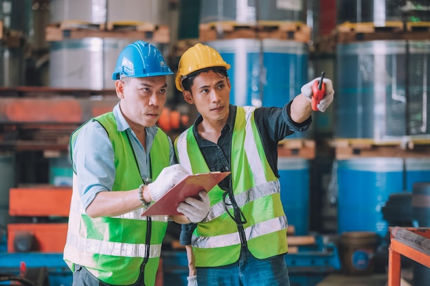 Aziatische ingenieur fabrieksmanager en monteur werknemer werknemer in veiligheidshelm praten en inspectie in de fabriek