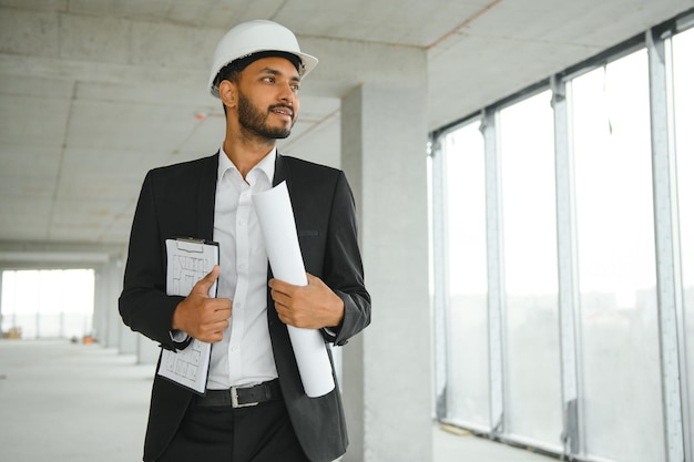 Aziatische ingenieur knappe man of architect met witte veiligheidshelm op de bouwplaats Staande op modern gebouw Arbeider Aziatische man aan het werk projectgebouw