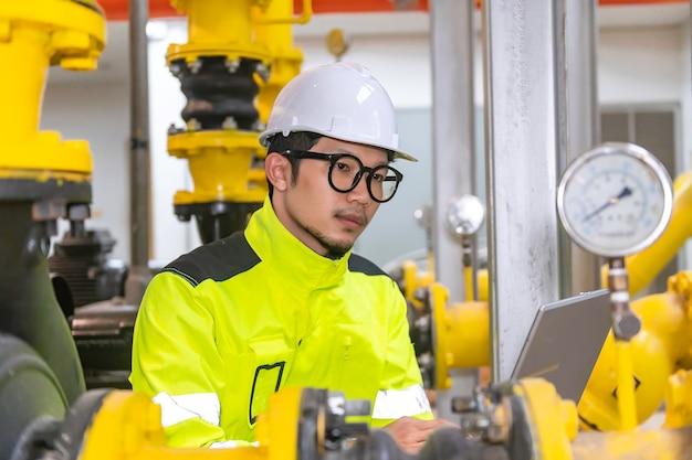 Aziatische ingenieur met een bril die in het stookruimteonderhoud werkt en technische gegevens van he