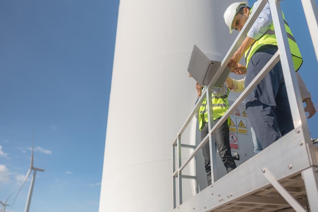 Aziatische ingenieur werkzaam in veldwerk buiten Werknemers controleren en inspecteren constructie en machine rond bouwproject Windturbine voor elektrische schone energie en duurzaam milieu