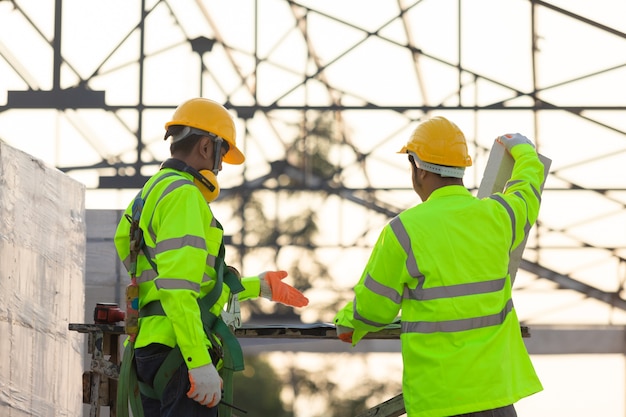 Aziatische ingenieurs en arbeiders die samen worden geraadpleegd voor bouwplanning en ontwikkelingsachtergrond is de structuur van het dak, Concept van bouwteamwerk.