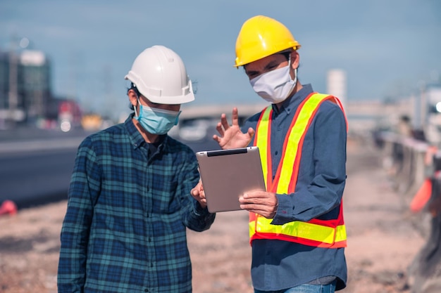 Aziatische ingenieursconstructie is een werknemer die werkt met een veiligheidshelm op de bouwplaats